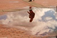 Reflections of a student in a spring puddle on a walk