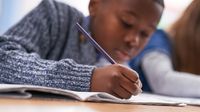 Elementary aged boy at school writing at desk