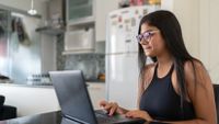 Teenage girl working on laptop in kitchen