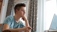 Boy doing homework at home on laptop
