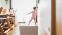 Pre-kindergarten aged girl dancing in front of laptop at home.