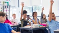 Students raise hands in middle school classroom 