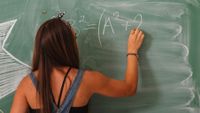 Teenage girl doing math problems on chalkboard