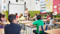 Teacher speaking to students in middle grade classroom 