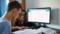 Teenage boy doing homework in front of computer