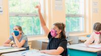 High school girl in classroom holding up hand