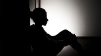 Silhouette of young teen girl sitting on floor