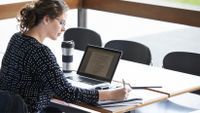Woman takes notes while working on her laptop