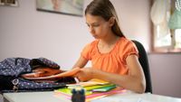 Middle school girl packing backpack at home