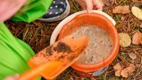 Child playing with mud in bucket