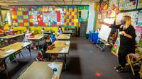 First grade classroom with students and teacher wearing masks while socially distanced