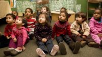 Pre-school students sitting on floor in classroom