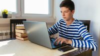 Teen boy working on his laptop at home