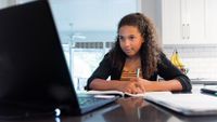Teenage girl participates in distance learning class at home with her laptop