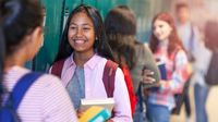 Middle school-aged girls chat in a school hallway