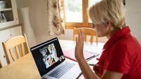 Teacher at home greeting students during online class
