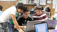 Middle school students work on a laptop together in their classroom