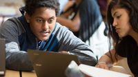 Two high school students collaborate in class using a laptop