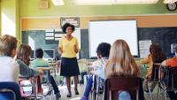 Middle school teacher instructs students from the front of the classroom