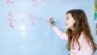 Elementary aged girl does math problem on whiteboard