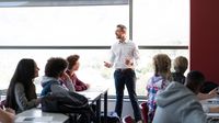 Teacher speaking to high school students in classroom.