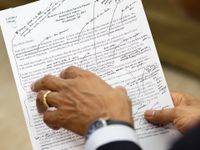 An employee of the Executive Office of the President of the United States is holding President Barack Obama's inaugural address. There are pen marks on it.