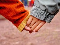 A closeup of two kids holding hands.