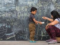 photo of a young person and adult in front of a chalkboard