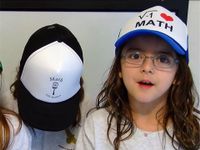 Three young girls are standing beside each other wearing hats that say, "I heart math."