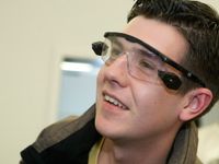 A closeup of a high school boy's face. He's smiling, looking off to the side, wearing tech goggles.