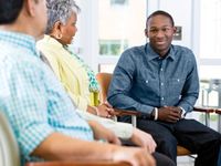 Young man speaking with two adults sitting in semi circle