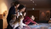 A group of students and teacher look at an illuminated table map.