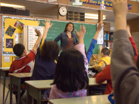 老师站在教室前面，学生举起手来
