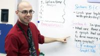 Man wearing glasses standing in front of a white board