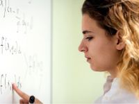 Close up of girl at white board doing a math problem