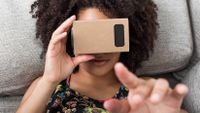 A young woman uses a cardboard virtual reality headset.