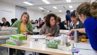 Teachers working together in groups of four with someone from the museum explaining a concept
