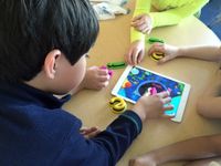 Four youngsters around desk using an app on a tablet