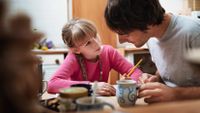 A man helping a girl with her homework the kitchen table