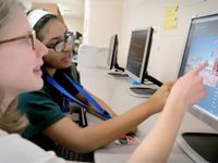 Photo of students pointing at computer screen