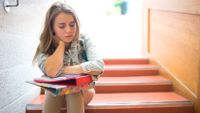 A student sits alone in a stairwell.