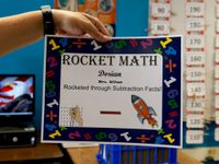 Teacher holding up Dorian's Rocket Math certificate that says he rocketed through subtraction facts