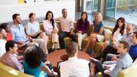 A photograph of a large group of adults sitting in a circle.