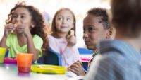 A group of young students enjoy snack time in their class.