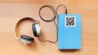 Image of a book with a pair of headphones attached