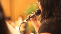 Photo of a student holding a microphone shot from behind and to one side