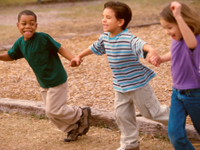 A photo of elementary school children holding hands and laughing.
