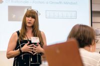 Woman standing in front of screen presenting to other teachers.