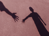 Shadow of two people reaching out their hands to each other