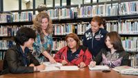 Teacher and four girls working together in the library